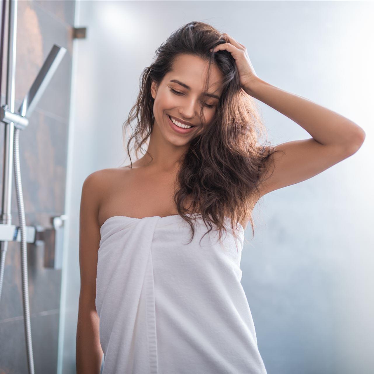 Porträt einer aufgeschlossenen Frau, die nach dem Baden steht und Haare mit der Hand hält
