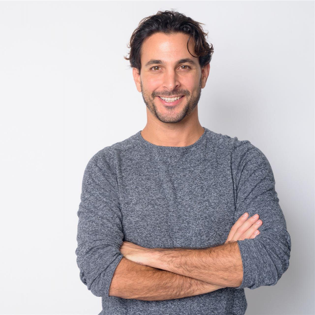 Porträt eines glücklichen, gutaussehenden hispanischen Mannes, der mit verschränkten Armen lächelt