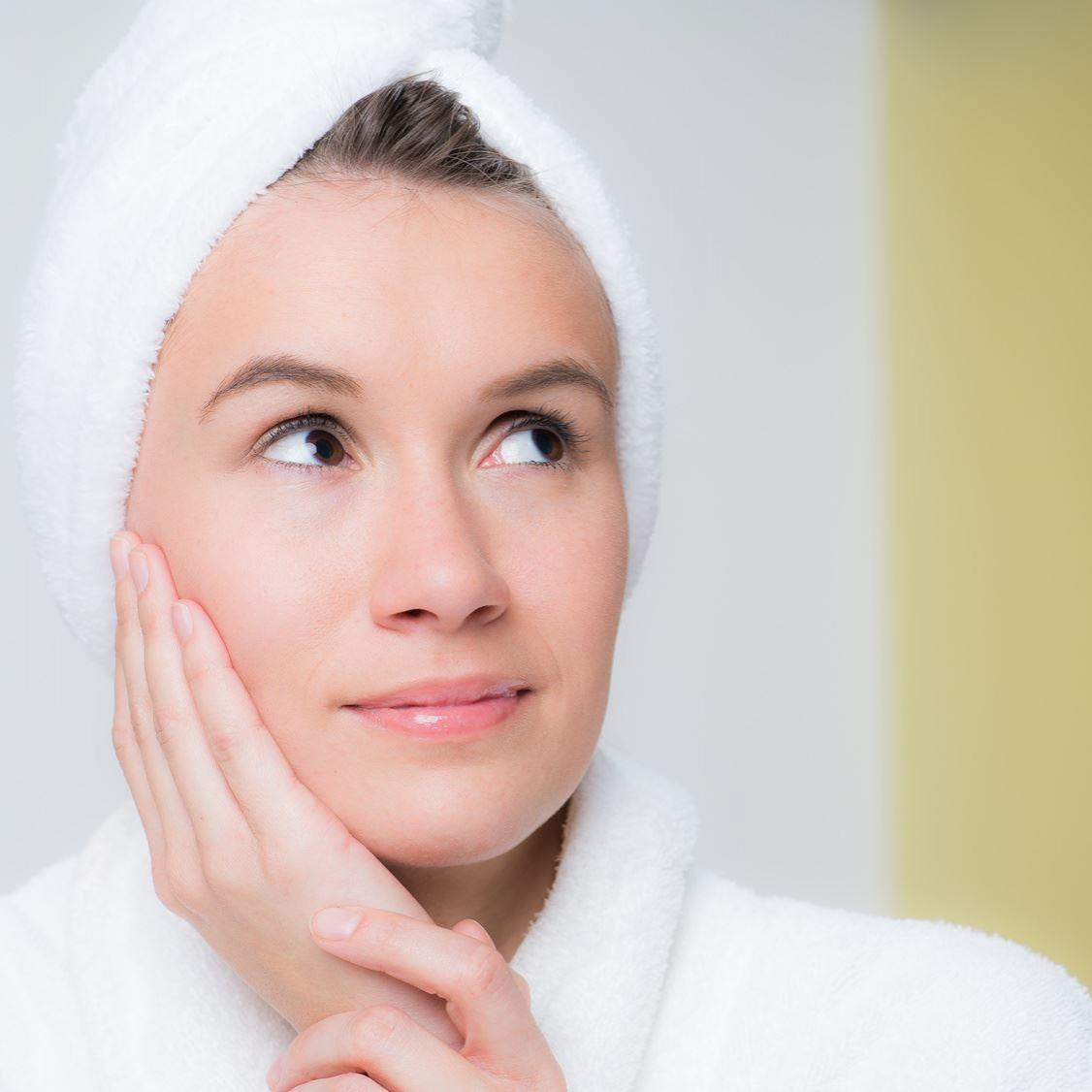 Zu sehen ist eine Frau mit Badetuch frau läßt eine haarkur einziehen 